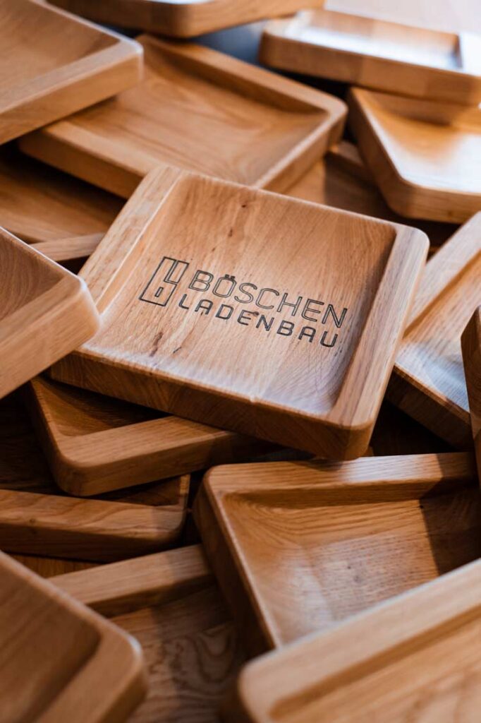 Stapel von Holzschalen mit Branding „Böschen Ladenbau“ auf der oberen Schale.