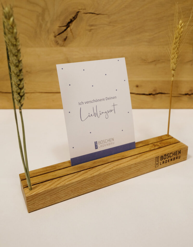 Holzaufsteller mit Ähren und Karte „Ich verschönere Deinen Lieblingsort“ von Böschen Ladenbau.